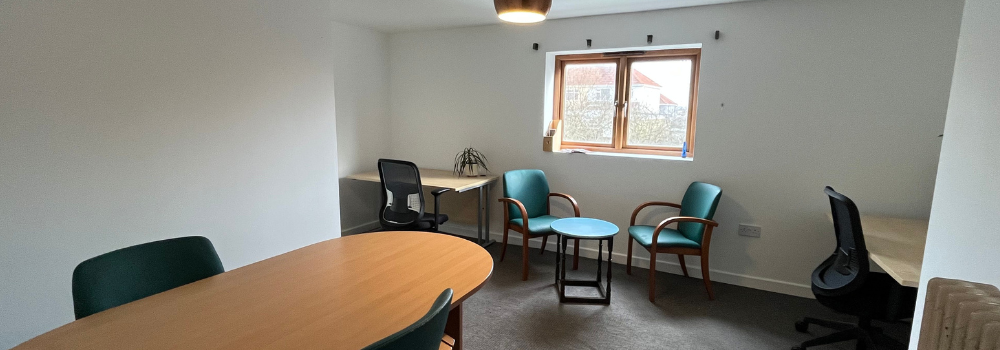 Private office space with large window, large conference desk and two side desks